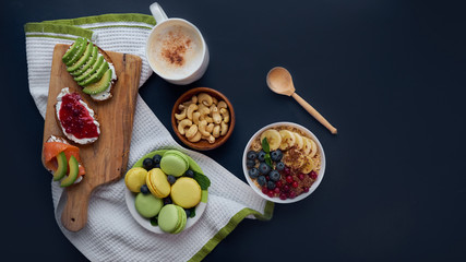breakfast top view black background. oatmeal with berries, toasts on a wooden tray, nuts, coffee