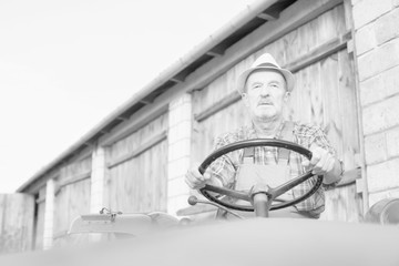 Black and white photo of senior farmer driving tractor