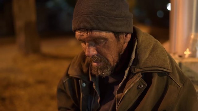 Face of lonely cold homeless man on the street at night.