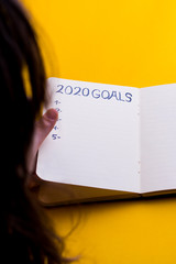 2020 new year goal,plan,action text on notepad with woman's hands.