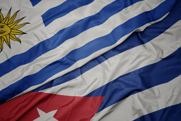 waving colorful flag of cuba and national flag of uruguay.