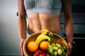 Close up of beautiful female muscle abdominal abs and mixed healthy fruit for fit lifestyle peope -...