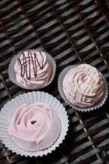 Aerial pink cherry marshmallows. Some in the shape of a rose, another decorated with chocolate. Against the background of wicker vines.