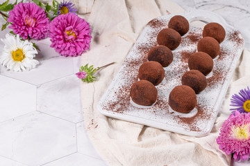 Fine chocolate truffles on white ceramic plate.