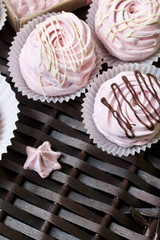 Aerial pink cherry marshmallows. Some in the shape of a rose, another decorated with chocolate. Against the background of wicker vines.