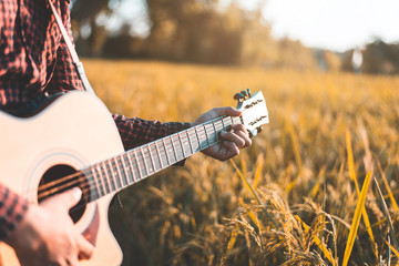 Country music, Man playing acoustic guitar in rice field, Focus on chord handle