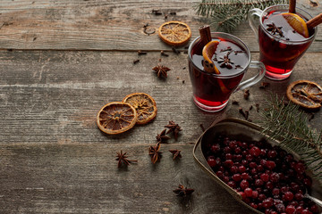 red spiced mulled wine with fir branch, berries, anise, orange slices and cinnamon on wooden rustic table
