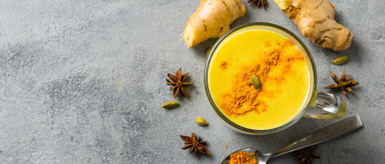 Golden yellow latte on light background. Indian drink turmeric golden milk in glass. Copy space Top...