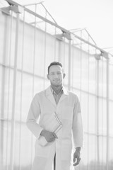 Black and white photo of crop scientist standing in greenhouse
