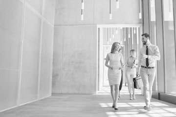 Fototapeta na wymiar Black and white photo of business people discussing plans before meeting while walking in office hall