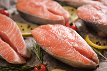 Raw, fresh salmon steaks on a baking tray with lemon, rosemary and cherry tomatoes. Raw salmon, red fish. Cooking salmon, seafood. Healthy eating concept. Salmon and spices