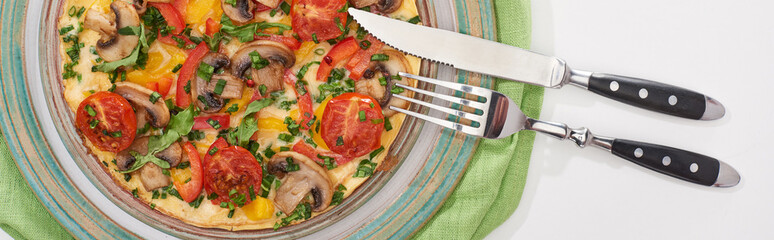top view of plate with tasty omelet for breakfast on white table with napkin, fork and knife