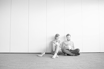 Black and white photo of business people eating lunch while sitting on the floor in office during break