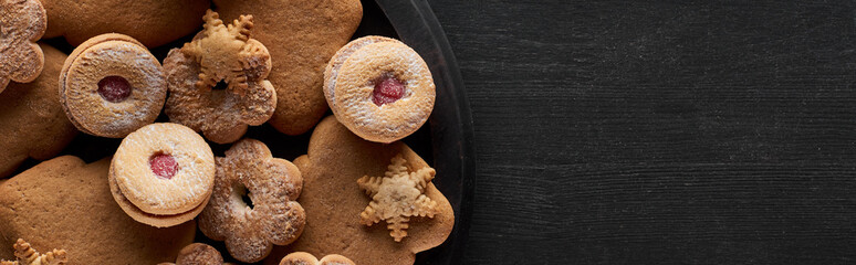 top view of Christmas cookies in pan on wooden black table, panoramic shot