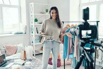 Beautiful young woman in casual clothing making social media video while spending time at home