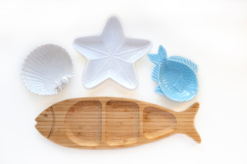 Empty wooden and ceramic plates in shape of fish, starfish and sea shell isolated on white background. Flat lay, top view