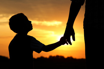 silhouette parent holds the hand of a  child
