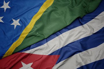waving colorful flag of cuba and national flag of Solomon Islands .