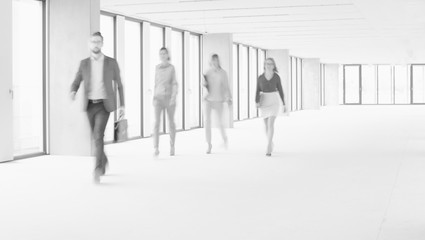 Black and white photo of business people walking in office hall