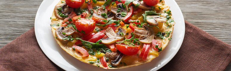 homemade omelet with vegetables on wooden table with napkin