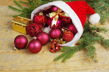 Santa Claus hat with colored balls and gifts on a wooden table.