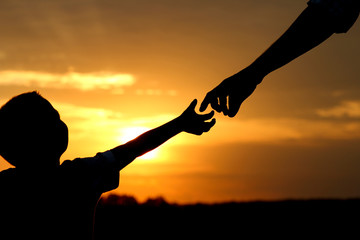 silhouette parent holds the hand of a  child