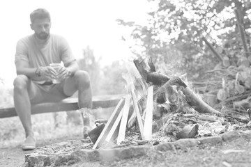 Black and white photo of man drinking beer in campfire