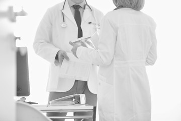 Doctors discussing over medical records at desk in hospital