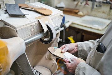 Obraz premium Professional craftsman of orthopedic insoles polishing, sanding and checking in his workshop the modeling of the templates with a fine sandpaper lathe. Hands covered in dust.