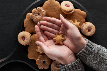 cropped view of woman holding snowflake cookie in hands