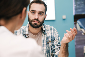 Image of female doctor and young patient man talking in hospital room