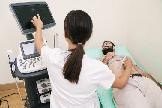 Image of young man getting abdominal ultrasound scan by female doctor