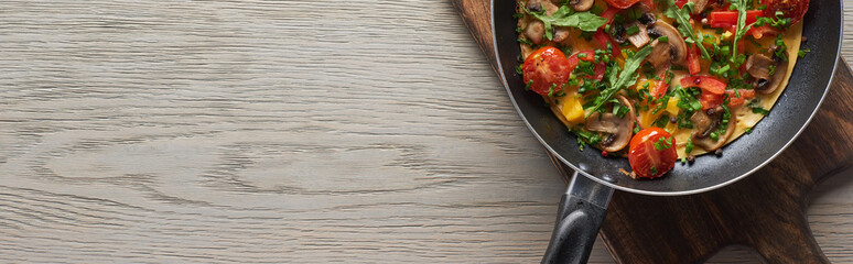 top view of tasty omelet in frying pan on wooden board