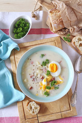 Traditional polish soup Zurek. Sour soup with sausage,  potatoes and eggs in ceramic bowl - 299096371