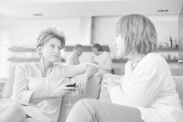 Mature women drinking wine while sitting in sofa at home