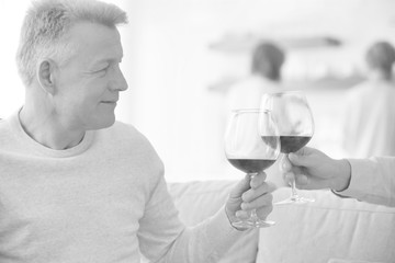 Mature friends drinking wine while sitting on sofa