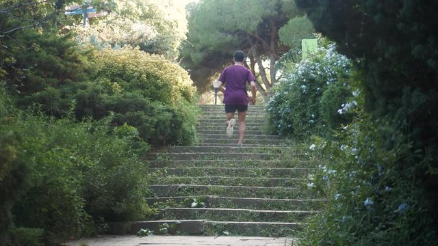 One young spanish latin athlete man is training running up and down the stairs in park, young runner football player