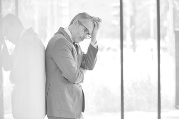 Stressed mature businessman standing at office