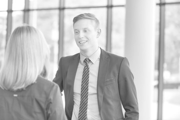 Black and white photo of Young businessman talking with businesswoman in office during meeting