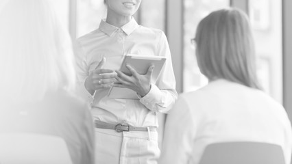 Black and white photo of Young businesswoman planning strategy with colleagues during meeting at office