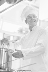Portrait of mature chef cooking on steel cooking pot in kitchen at restaurant