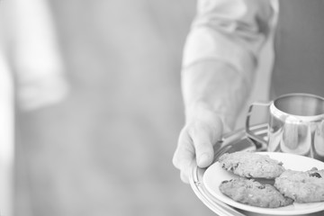 Young waiter serving coffee and cookies at restaurant
