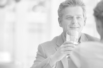Smiling mature man sitting with young woman at table in restaurant