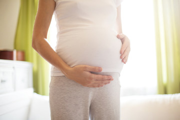 Pregnant woman standing near window at home
