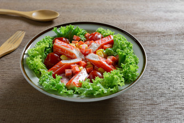 close up of crab stick salad in a ceramic dish on wooden table. homemade style healthy food concept.