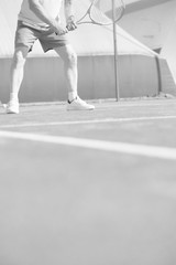 Confident mature man hitting tennis ball with racket on red court