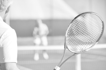 Active seniors playing tennis on sunny day at red court