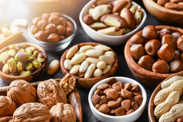 Fotobehang Mixed nuts in wooden bowls on black stone table. Almonds, pistachio, walnuts, cashew, hazelnut. Top view nut photo. © Milan