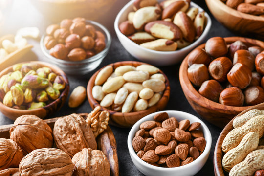 Mixed nuts in wooden bowls on black stone table. Almonds, pistachio, walnuts, cashew, hazelnut. Top view nut photo.