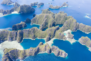 Highly eroded limestone islands rise from the beautiful, tropical seascape in Raja Ampat, Indonesia. This remote region is known for its extraordinary marine biodiversity. © ead72